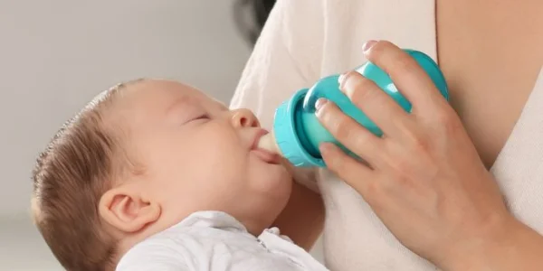 Bebé alimentándose con leche de un biberón